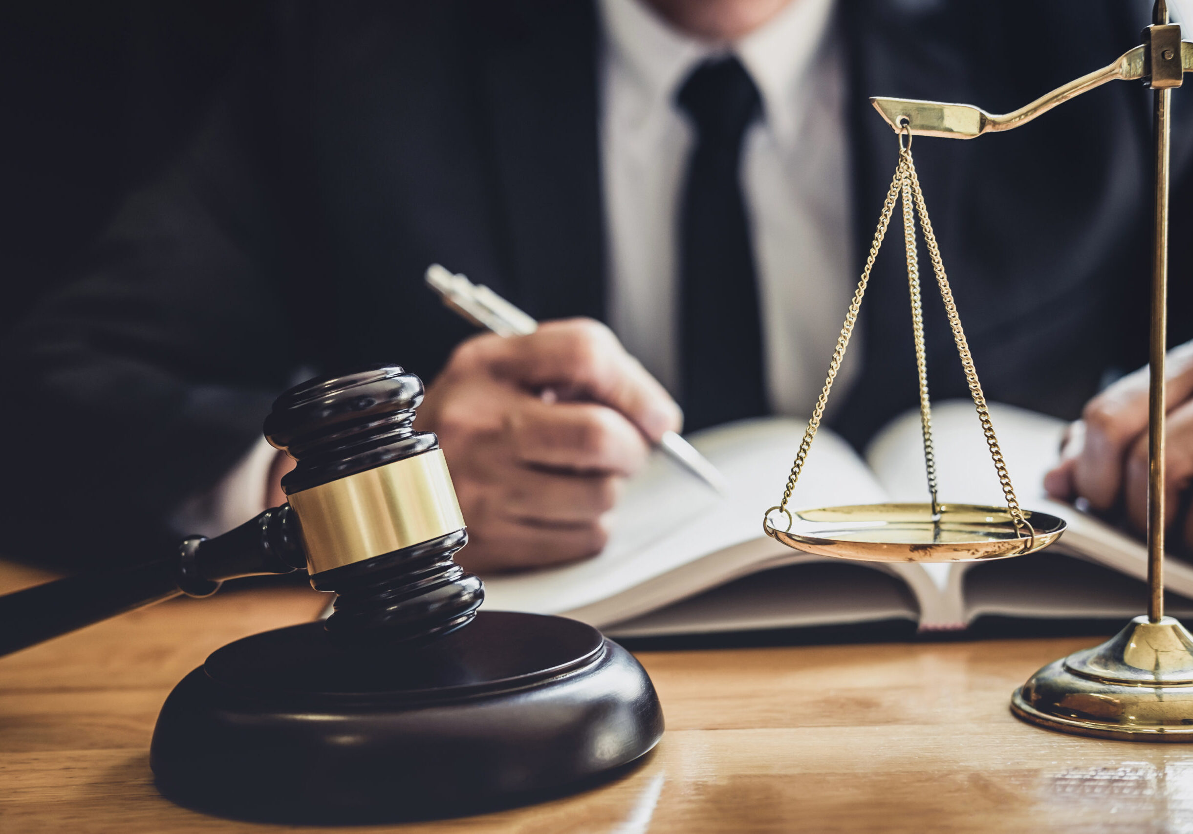 Male lawyer or judge working with contract papers, Law books and wooden gavel on table in courtroom, Justice lawyers at law firm, Law and Legal services concept.